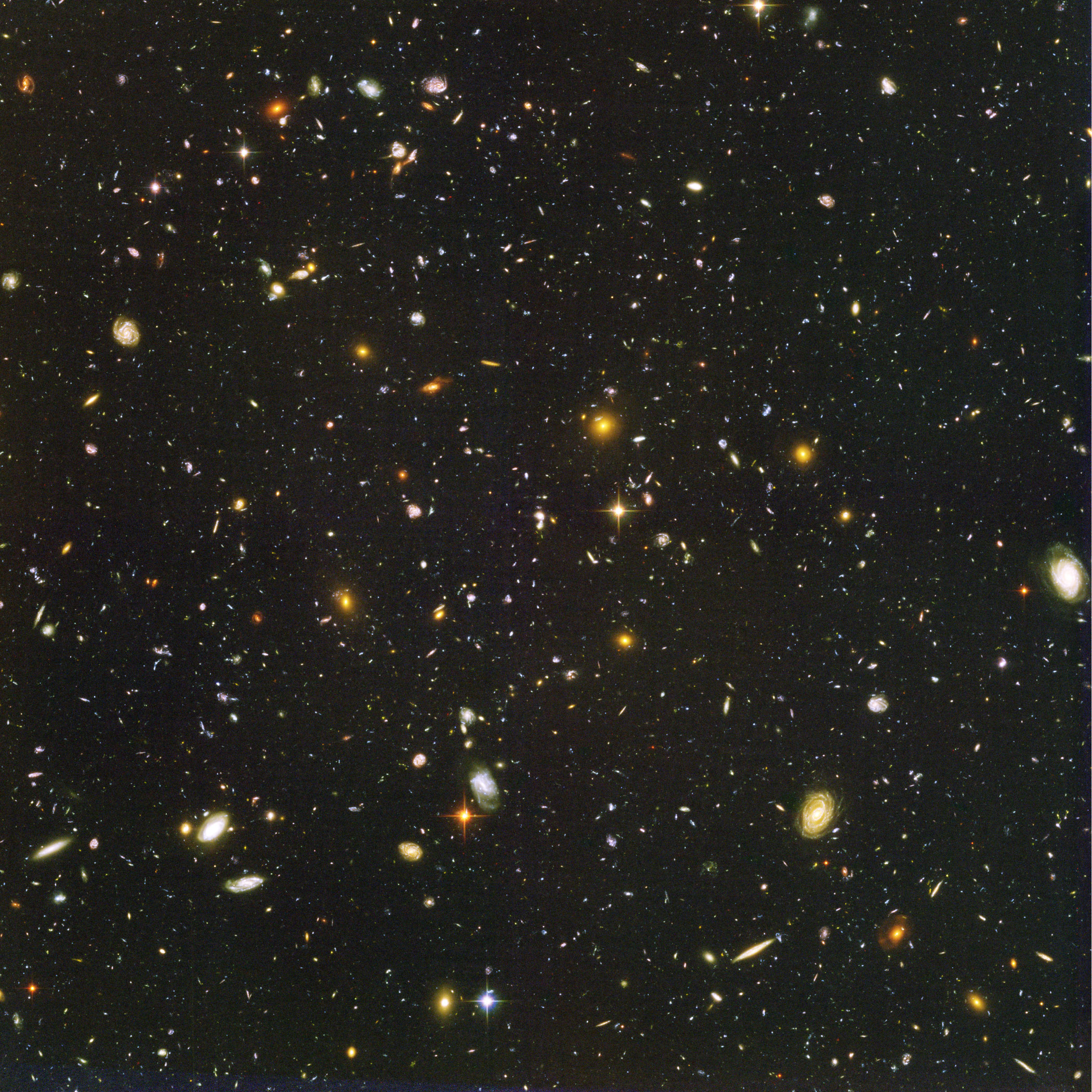 The Hubble Ultra Deep Field, a dense black field scattered with thousands of distant galaxies and a few bright foreground objects.